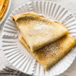 two crepes on a plate with recipe ingredients nearby.