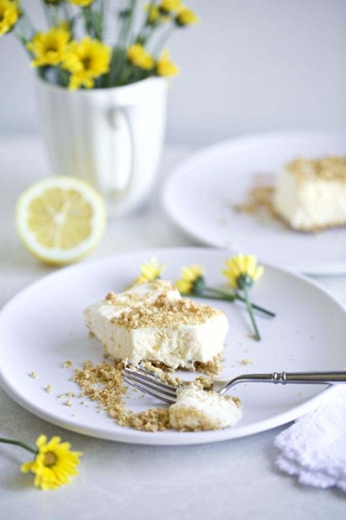 Creamy Frozen Lemon dessert with graham cracker crust on a plate with yellow flowers