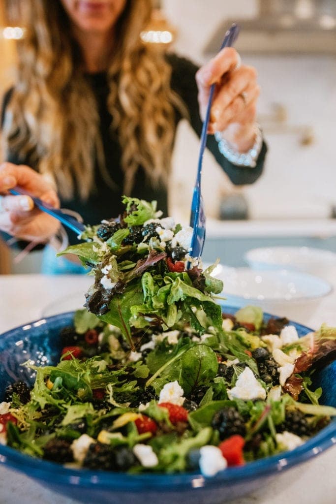 Berry and Goat Cheese Salad with Honey Citrus Dressing tossing salad