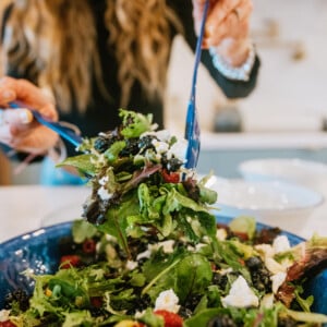 Berry and Goat Cheese Salad with Honey Citrus Dressing tossing salad