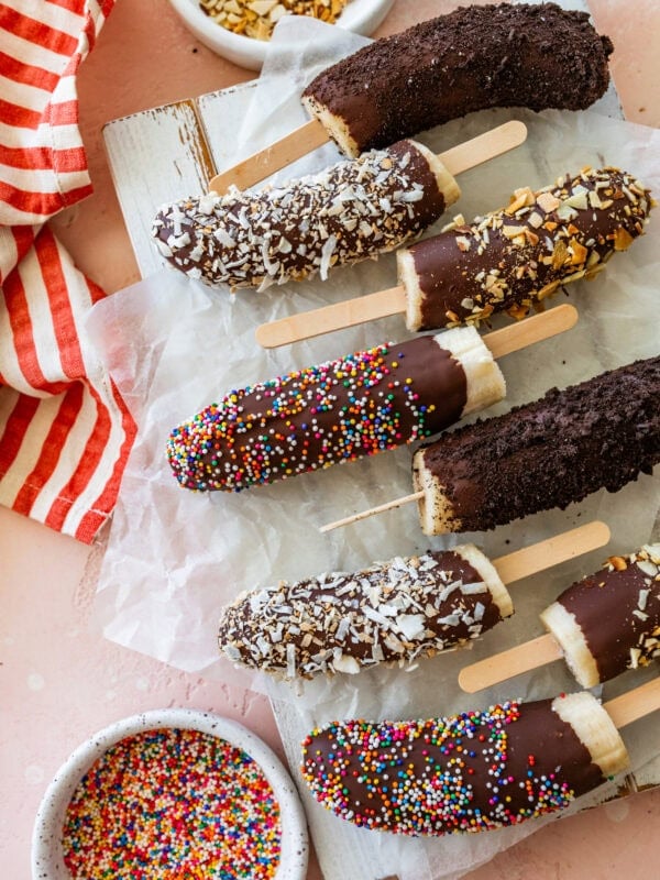 a few chocolate dipped bananas with toppings laid next to each other.
