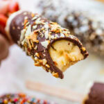 One chocolate dipped banana with a bite taken out of it.