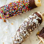 a few chocolate dipped bananas with toppings laid next to each other.