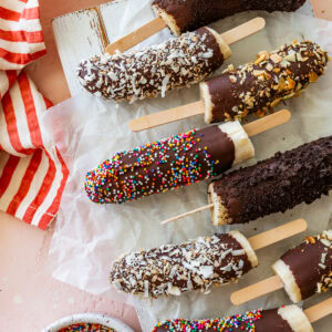 a few chocolate dipped bananas with toppings laid next to each other.