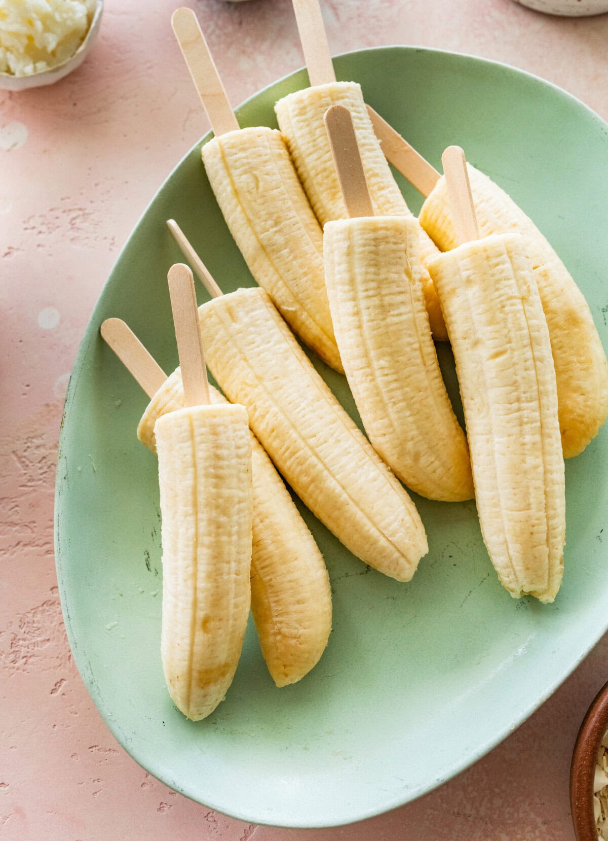 a tray of bananas that have been put on popsicle sticks.