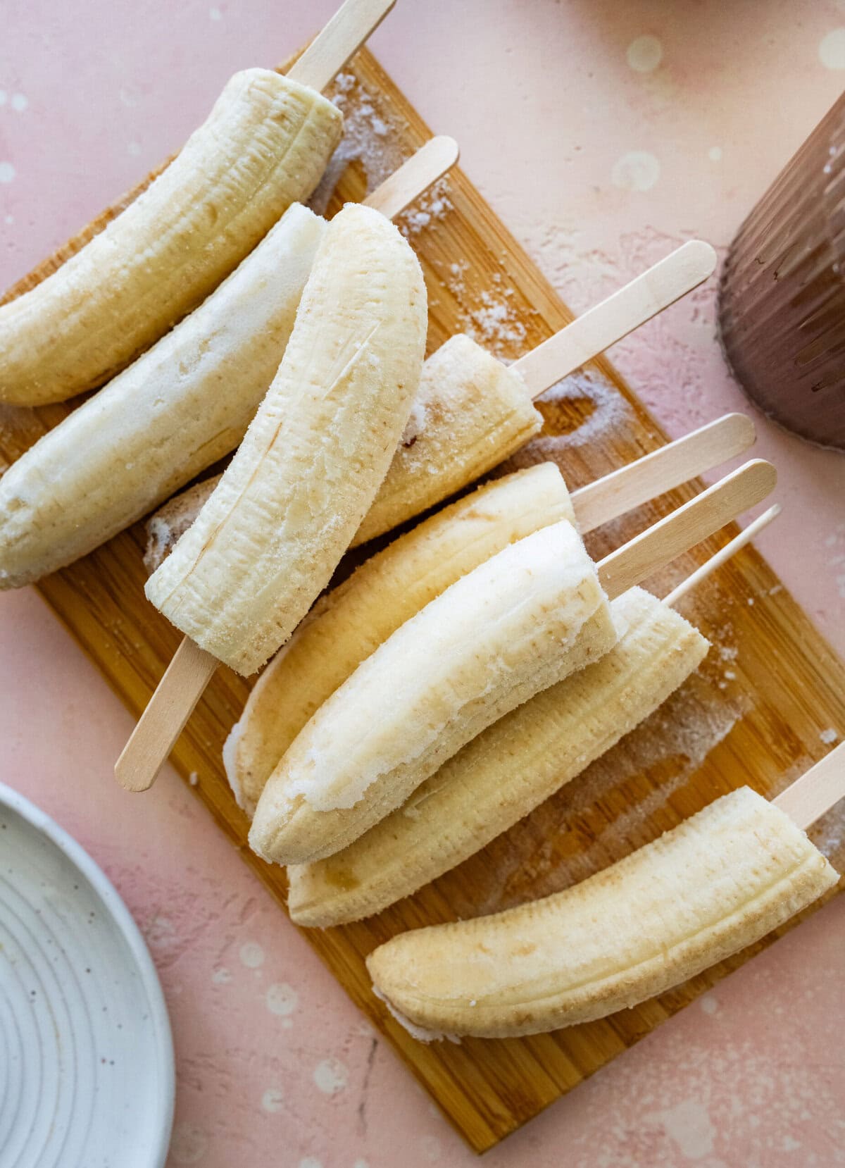 a tray of bananas that have been put on popsicle sticks and frozen.