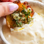 Dipping one smashed potato into a small bowl of aioli.