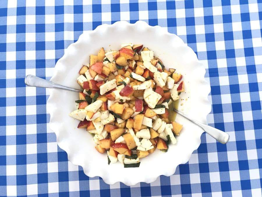 Peach and mozzarella salad in a big white bowl.