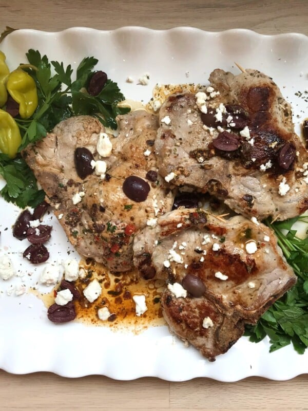 White, fluted plate of Mediterranean stuffed pork chops.