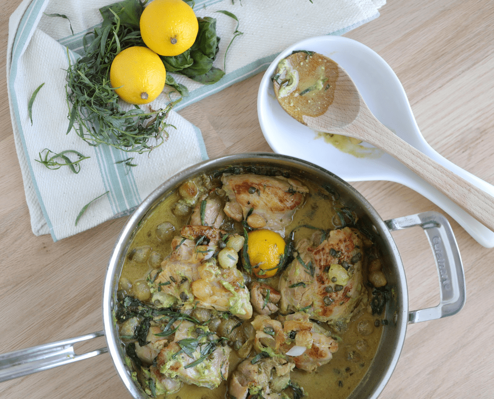 Chicken and ingredients in a plot with spoons on a counter.