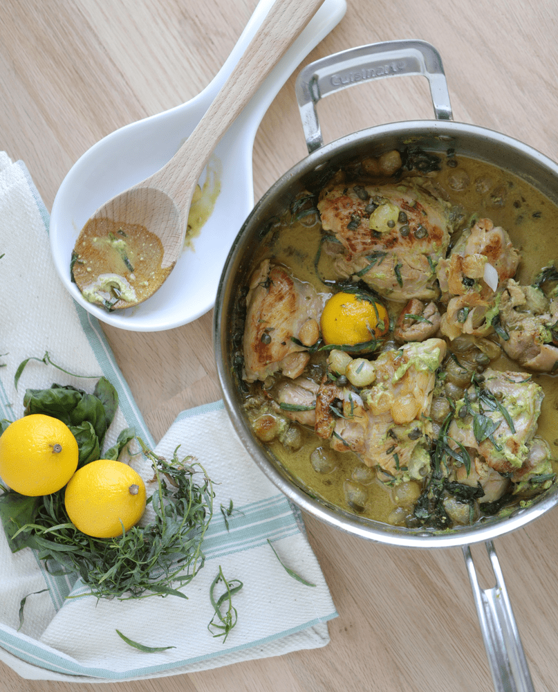 Chicken and ingredients in a plot with spoons on a counter.