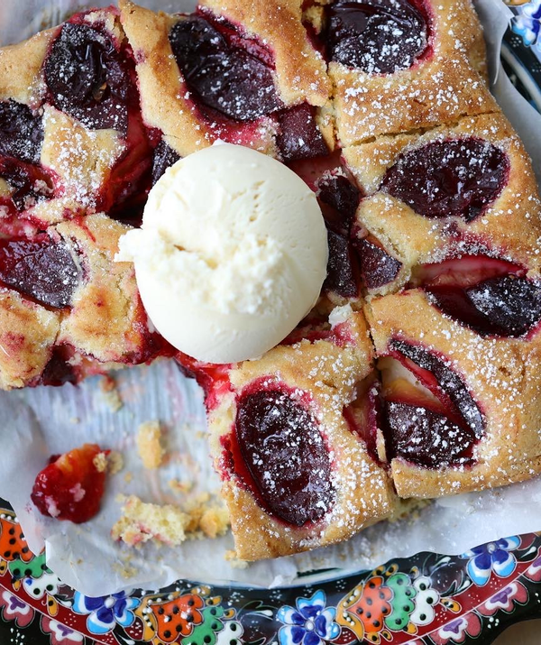 Sliced plum torte topped with ice cream.
