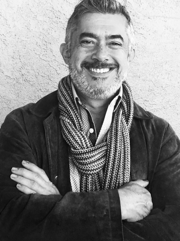 Black and white photo of a man smiling and wearing a scarf.