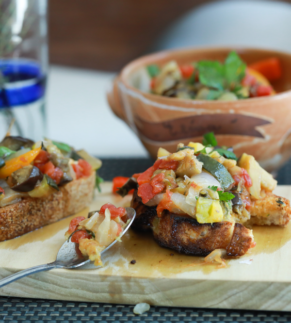 Ratatouille tartine on a wooden board with a spoon.