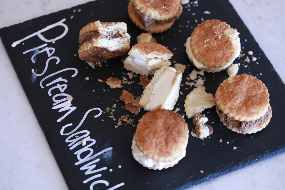 Ice cream sandwiches with pie crust on a black board saying Pies Cream Sandwiches.