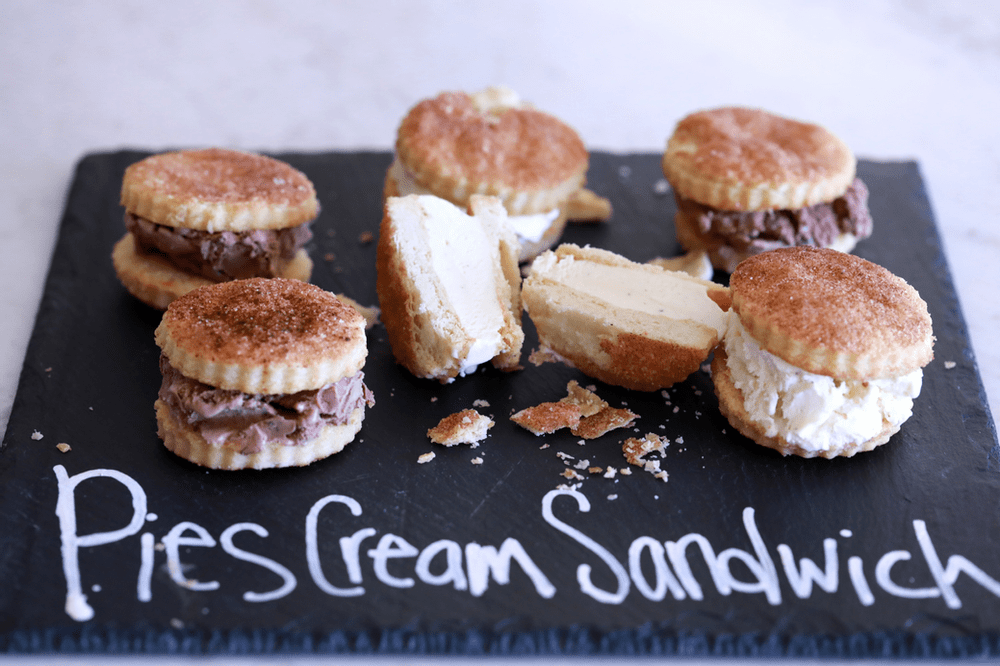 Ice cream sandwich with pie crust on a black board reading "Pies Cream Sandwich".