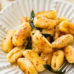 A bowl of brown butter sage gnocchi with a utensil resting inside.