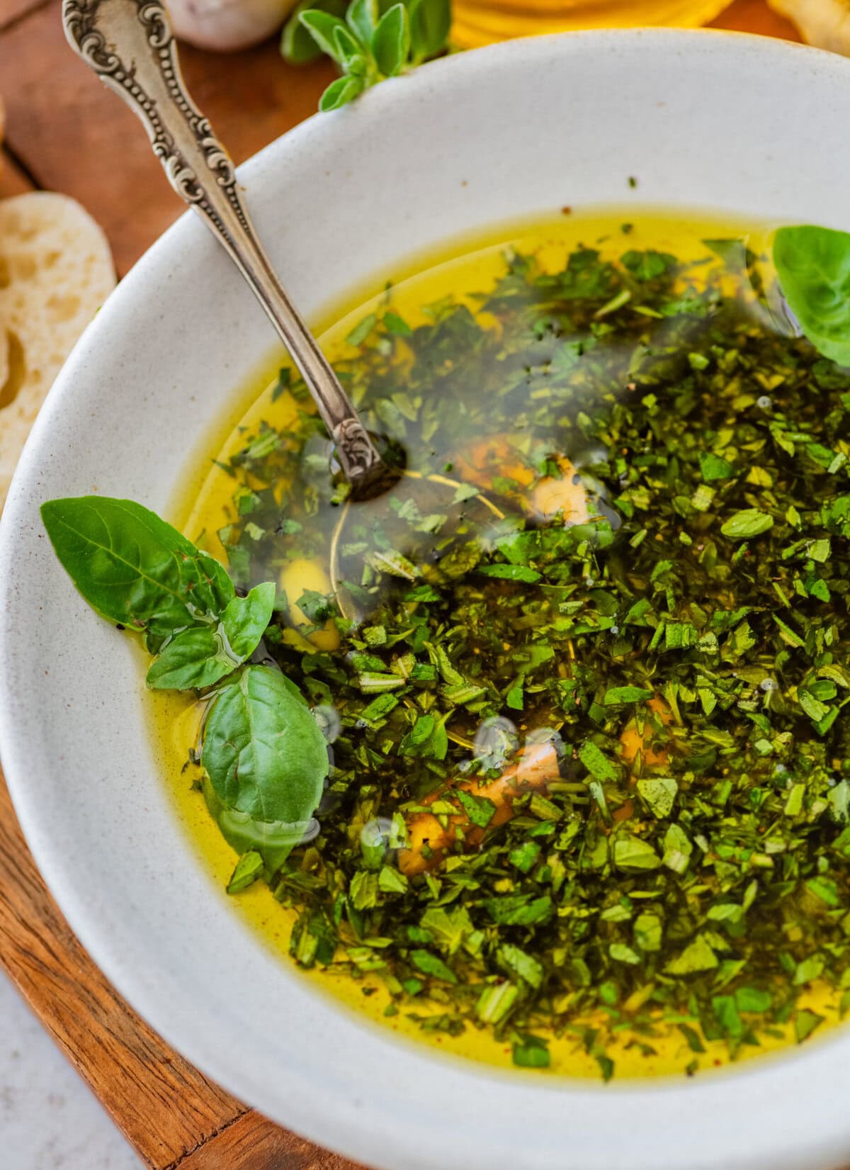 A bowl of olive oil bread dip garnished with fresh basil leaves.