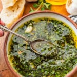 A bowl of bread dipping oil with a spoon resting in the bowl.