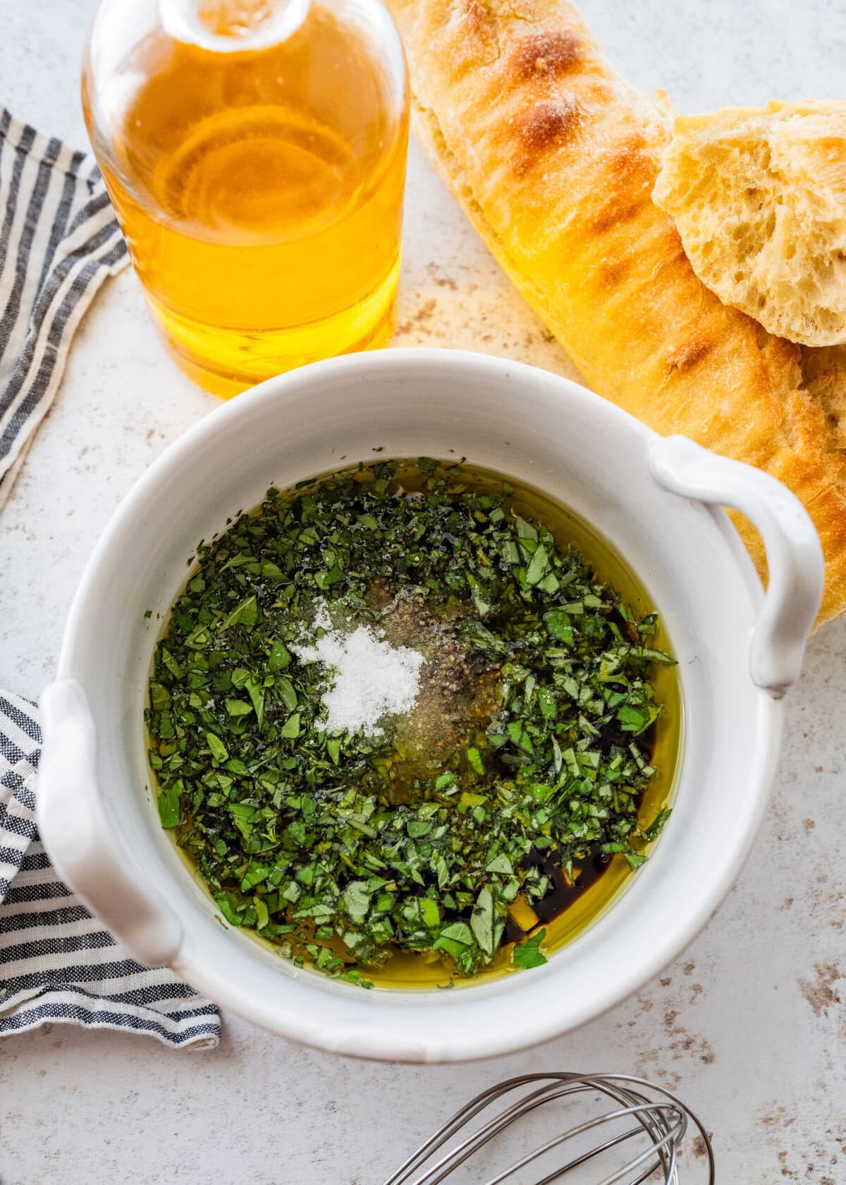 Adding the chopped herbs to the bowl of olive oil.