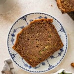 A slice of zucchini brad on a plate, with more ingredients nearby.
