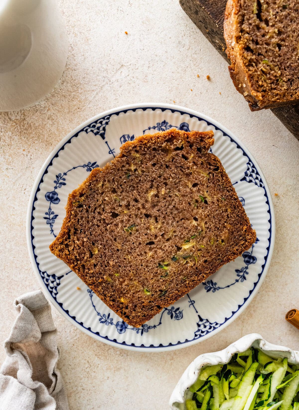 A slice of zucchini brad on a plate, with more ingredients nearby.