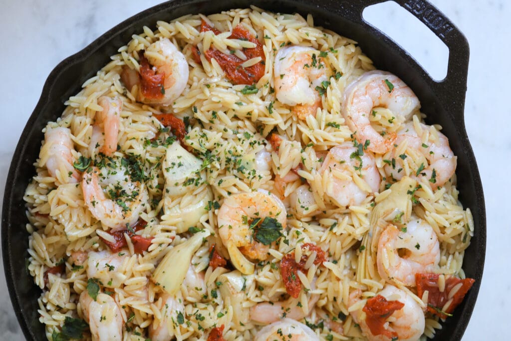 Orzo shrimp pasta in a black skillet.