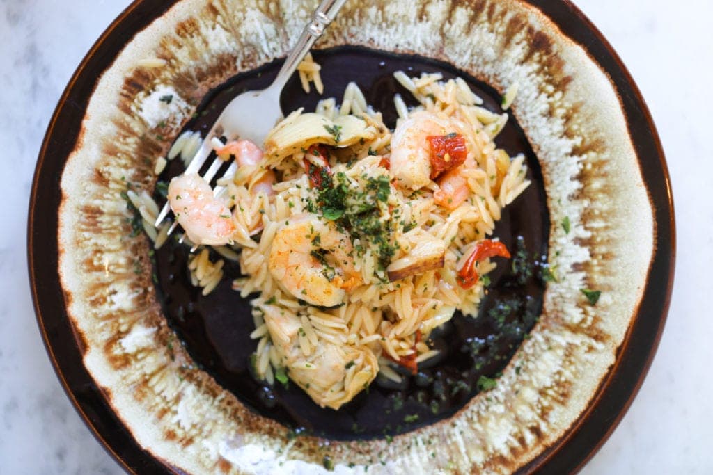 Orzo shrimp pasta in a black skillet.