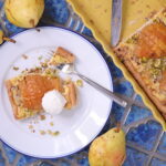 Piece of pear and frangipane tart on a plate with a fork.