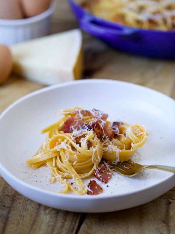 Carbonara recipe on a plate ready to eat. Pieces of bacon on top.