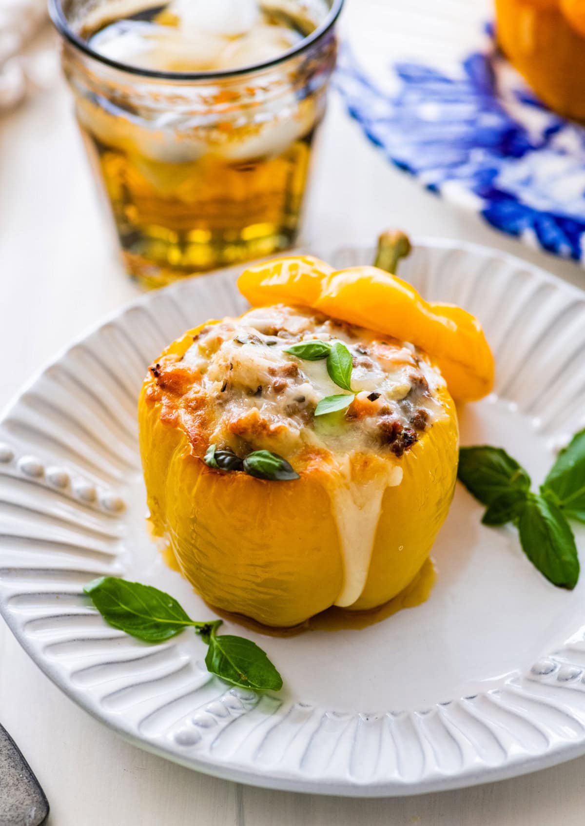A single Italian stuffed pepper on a plate garnished with fresh basil leaves.