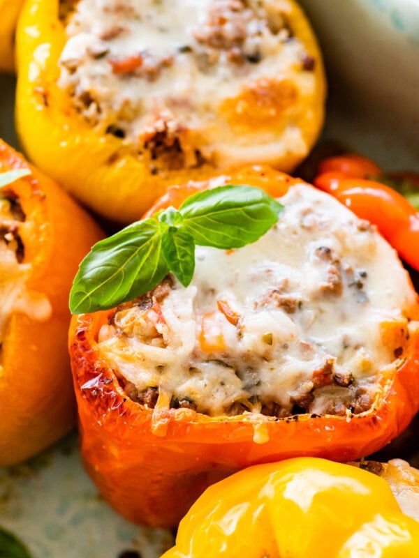 Italian stuffed peppers in a dish garnished with fresh basil and melted cheese.