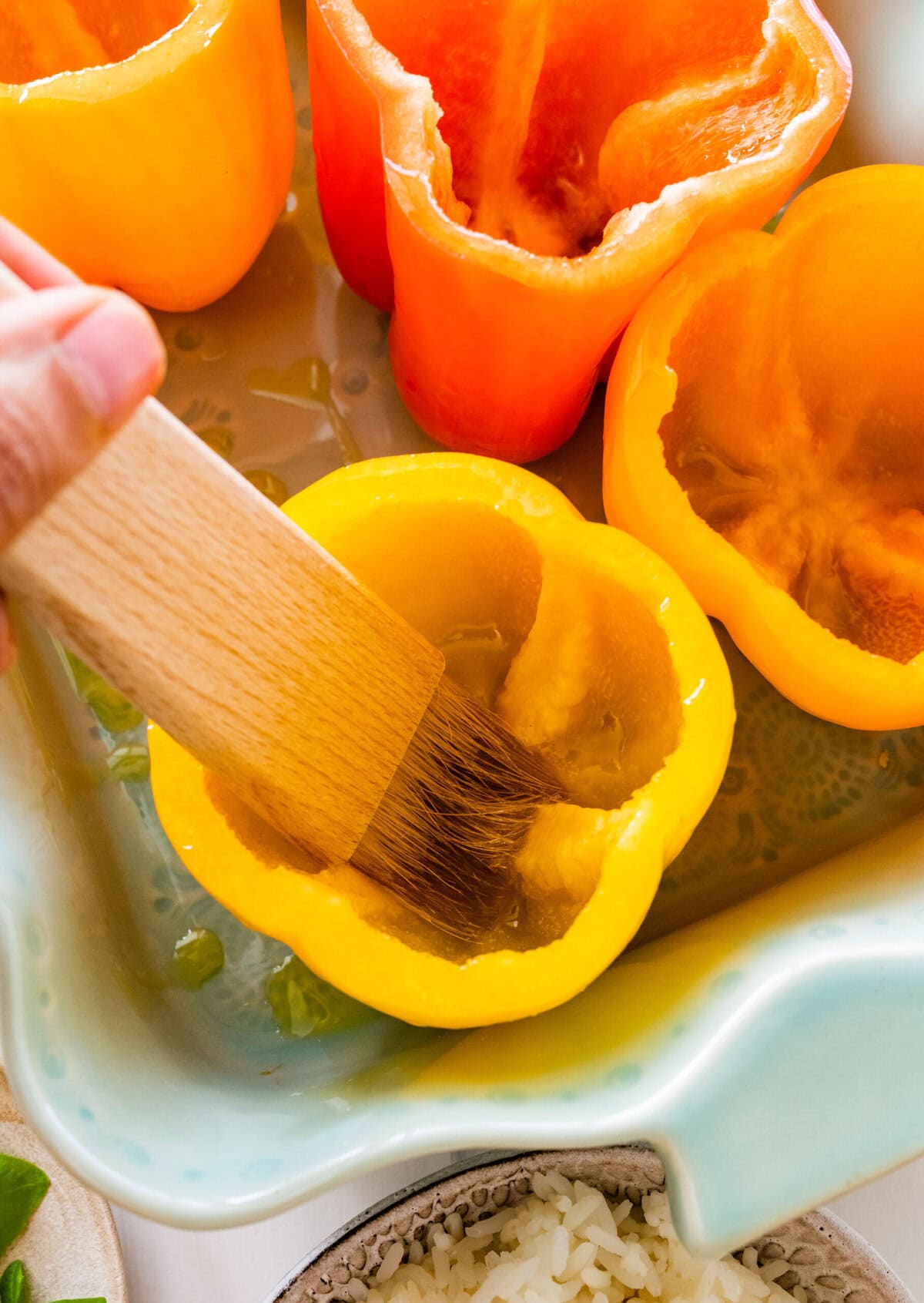 Brushing an scooped out bell pepper with olive oil.
