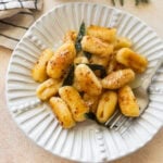 A plate of brown butter sage gnocchi with a fork resting on it.