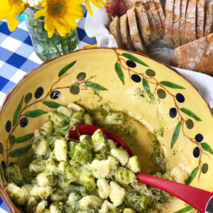 Red spoon in a bowl of homemade potato gnocchi.