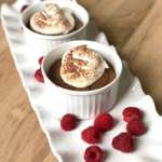 Small bowls of chocolate mousse on a long white tray.