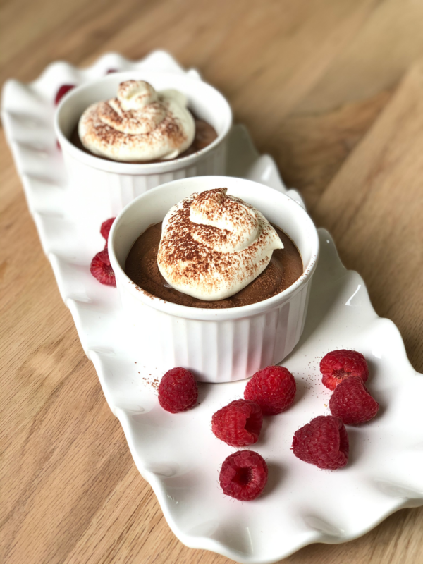 Small bowls of chocolate mousse on a long white tray.