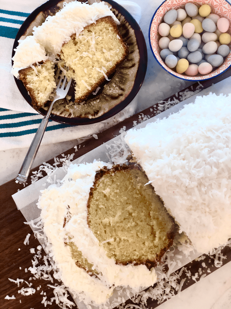 Coconut cake sliced on a cutting board and in a bowl.