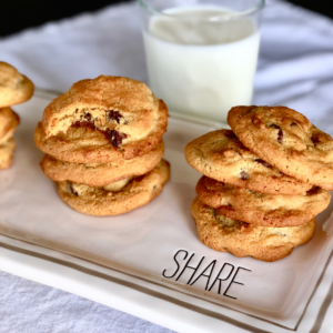 Piles of chocolate chippers cookies on a platter that reads "Share."