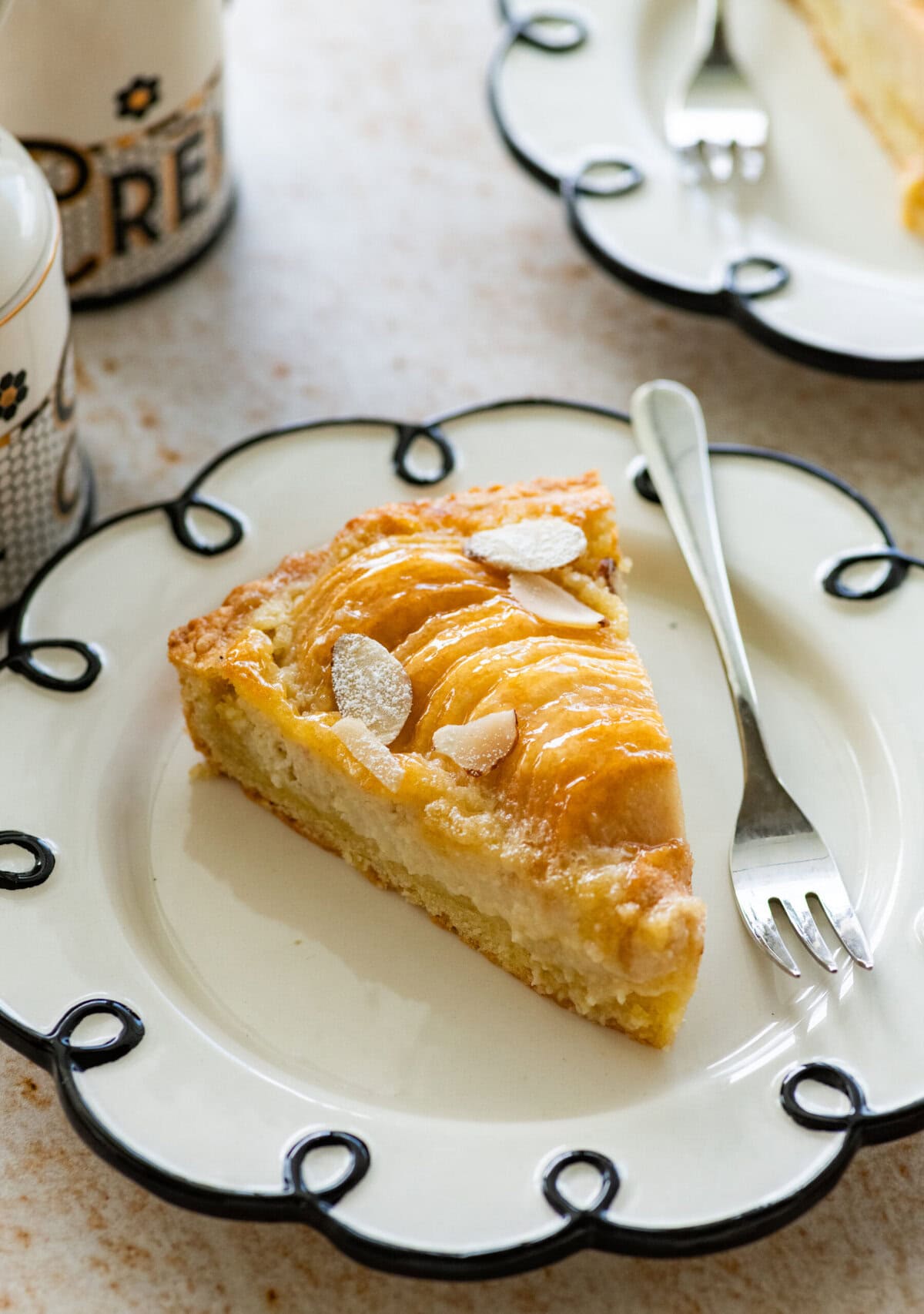 A slice of pear frangipane tart on a plate with a fork.