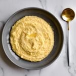 creamy polenta on a marble background with a spoon on the side.