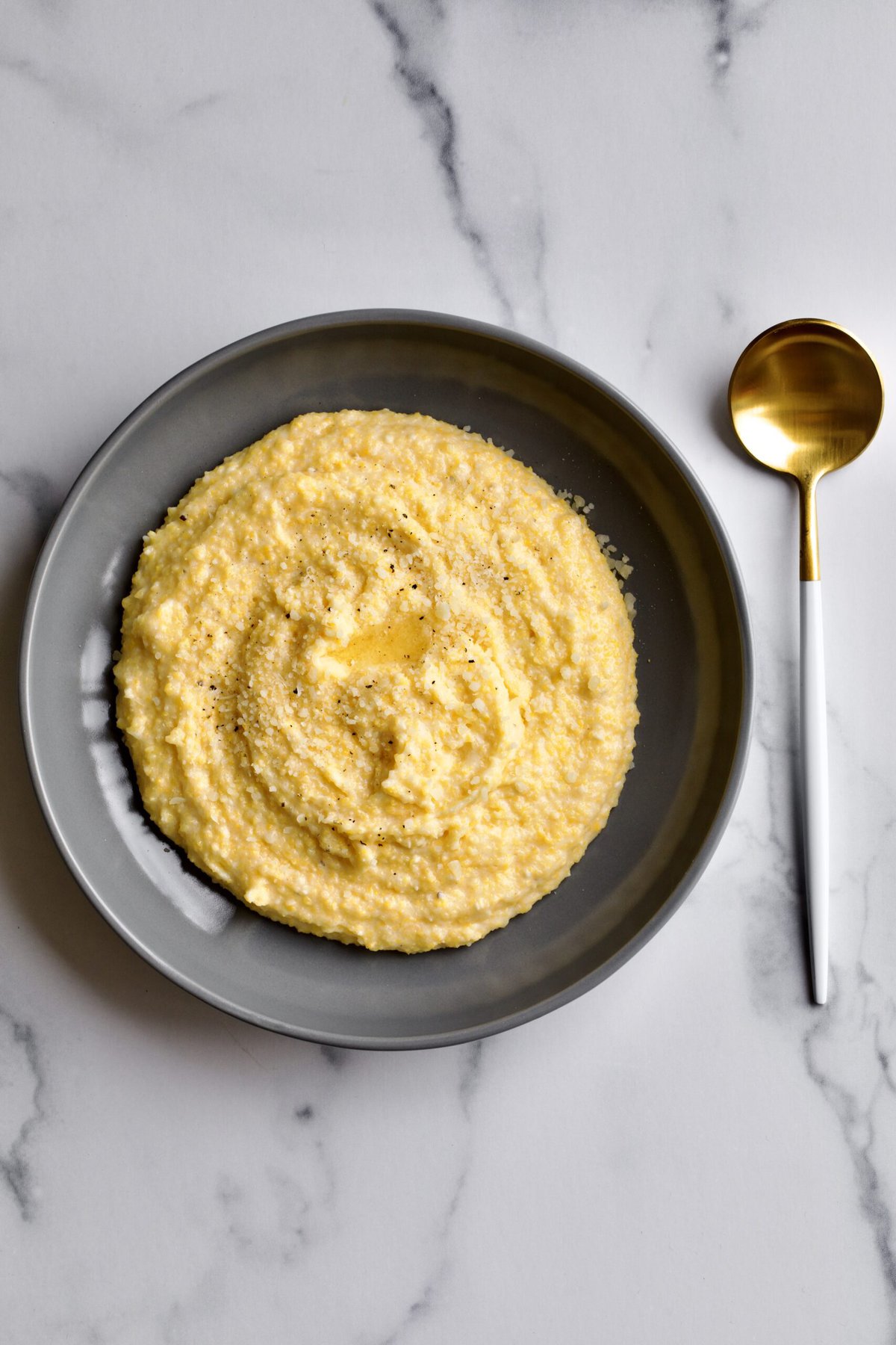 creamy polenta on a marble background with a spoon on the side. 