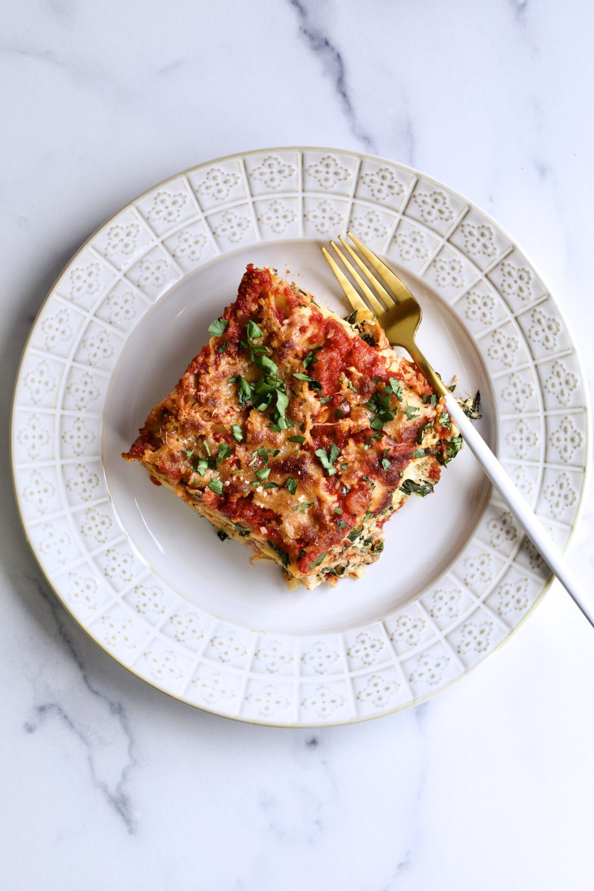 spinach and ricotta lasagna slice on a white plate.