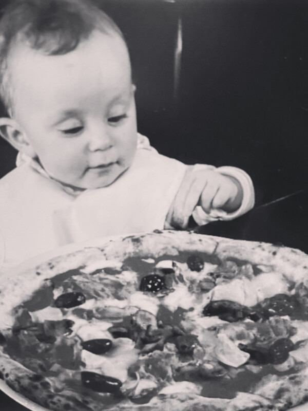 Black and white photo of a child with a pizza.