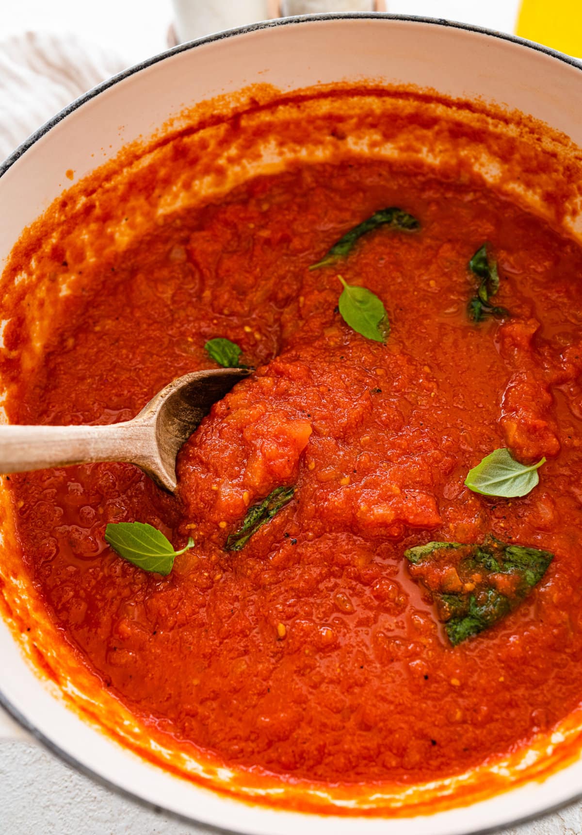 wooden spoon inside the pot of Italian tomato sauce and stirring.