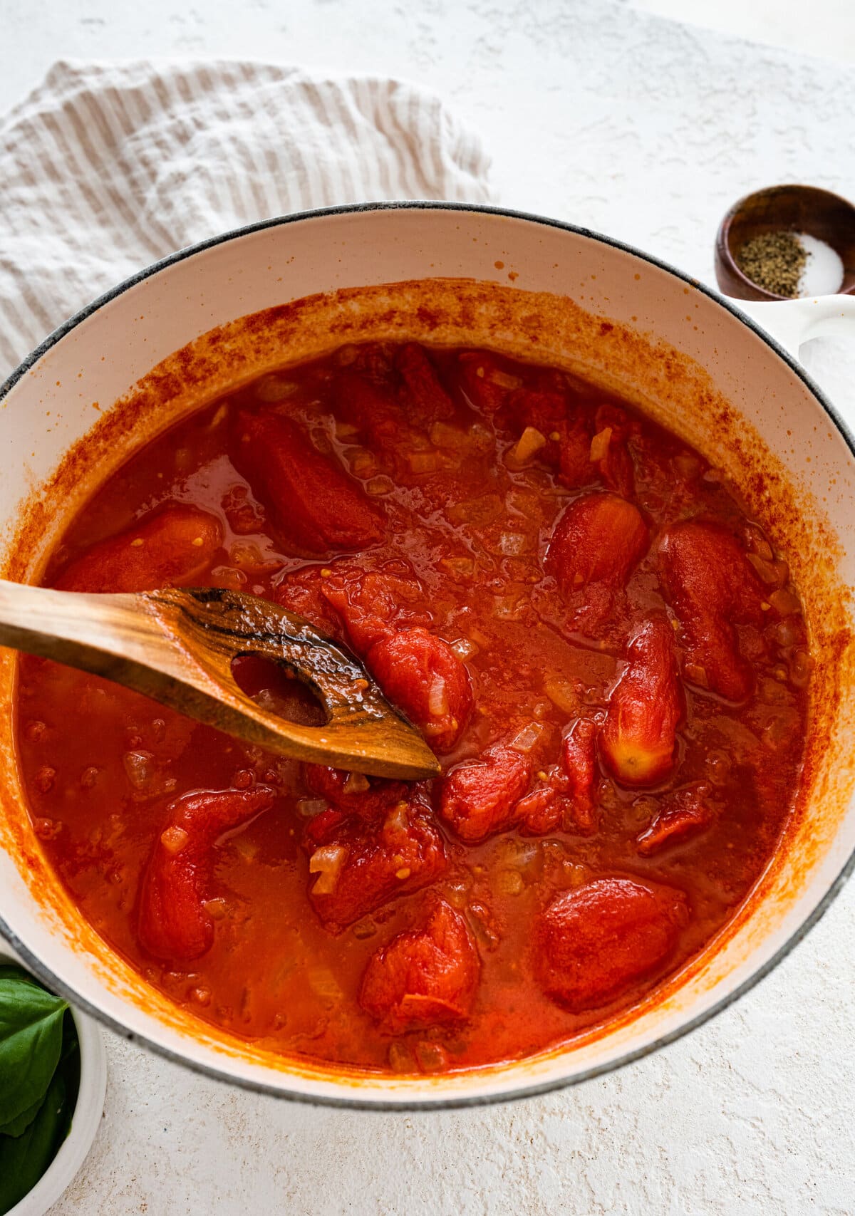 how to make sugo al pomodoro step-by-step photos: smashing the whole canned tomatoes with a wooden spoon.