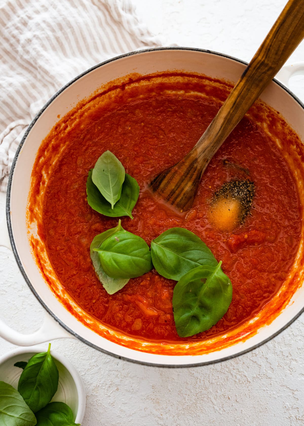 how to make sugo al pomodoro step-by-step photos: adding fresh basil on top of sauce and stirring.
