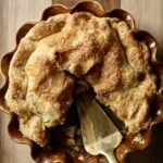 Brown butter apple pie in a brown pie pan missing a slice.