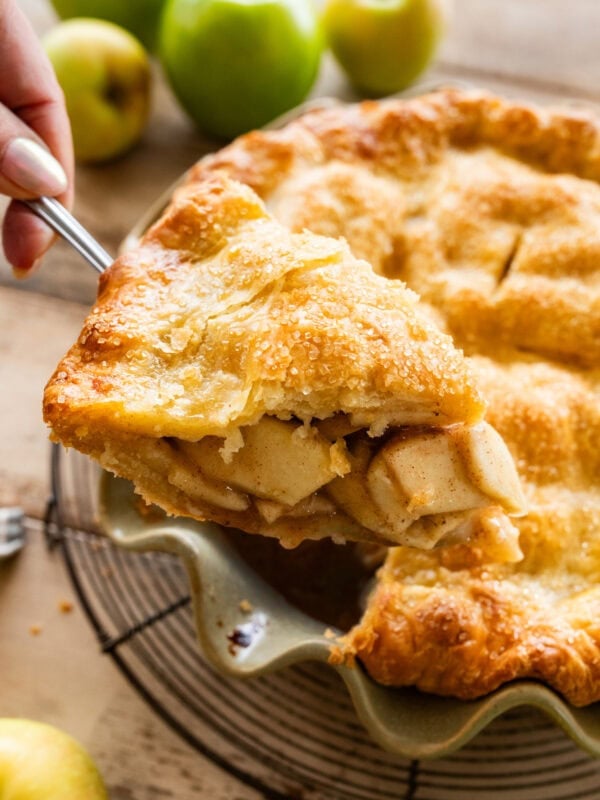 A piece of apple pie being removed from the pie dish.