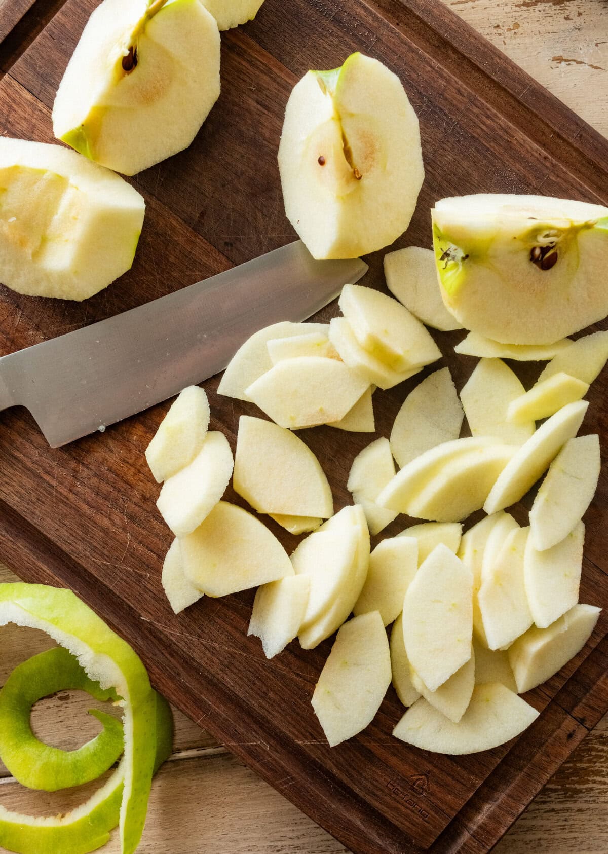 Cut up apple pieces on a cutting board with a knife.